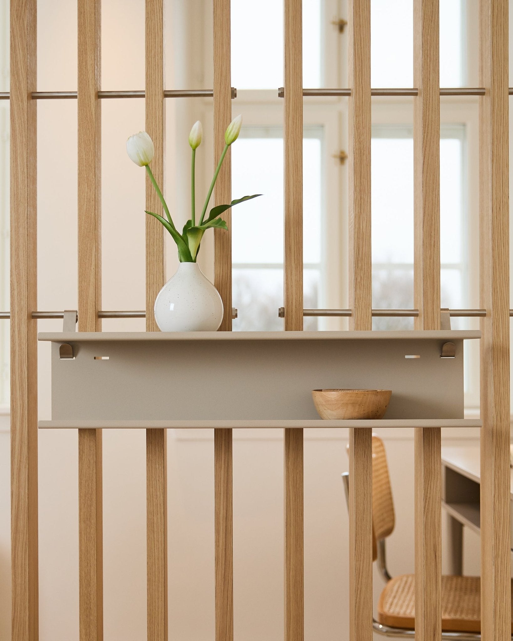 Double Metal Shelf / BM1 by WoodUpp in beige (63.5 cm) mounted on a slatted room divider, styled with a vase and wooden bowl.
